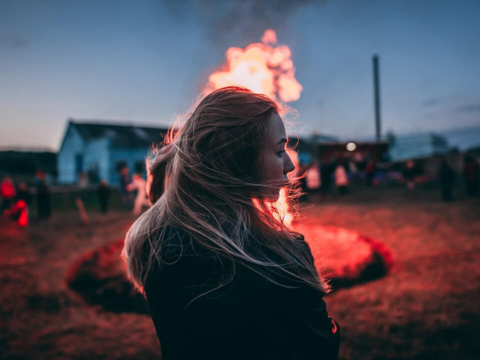 A woman stands confidently in front of a bonfire, symbolizing hope and innovation for a sustainable future.